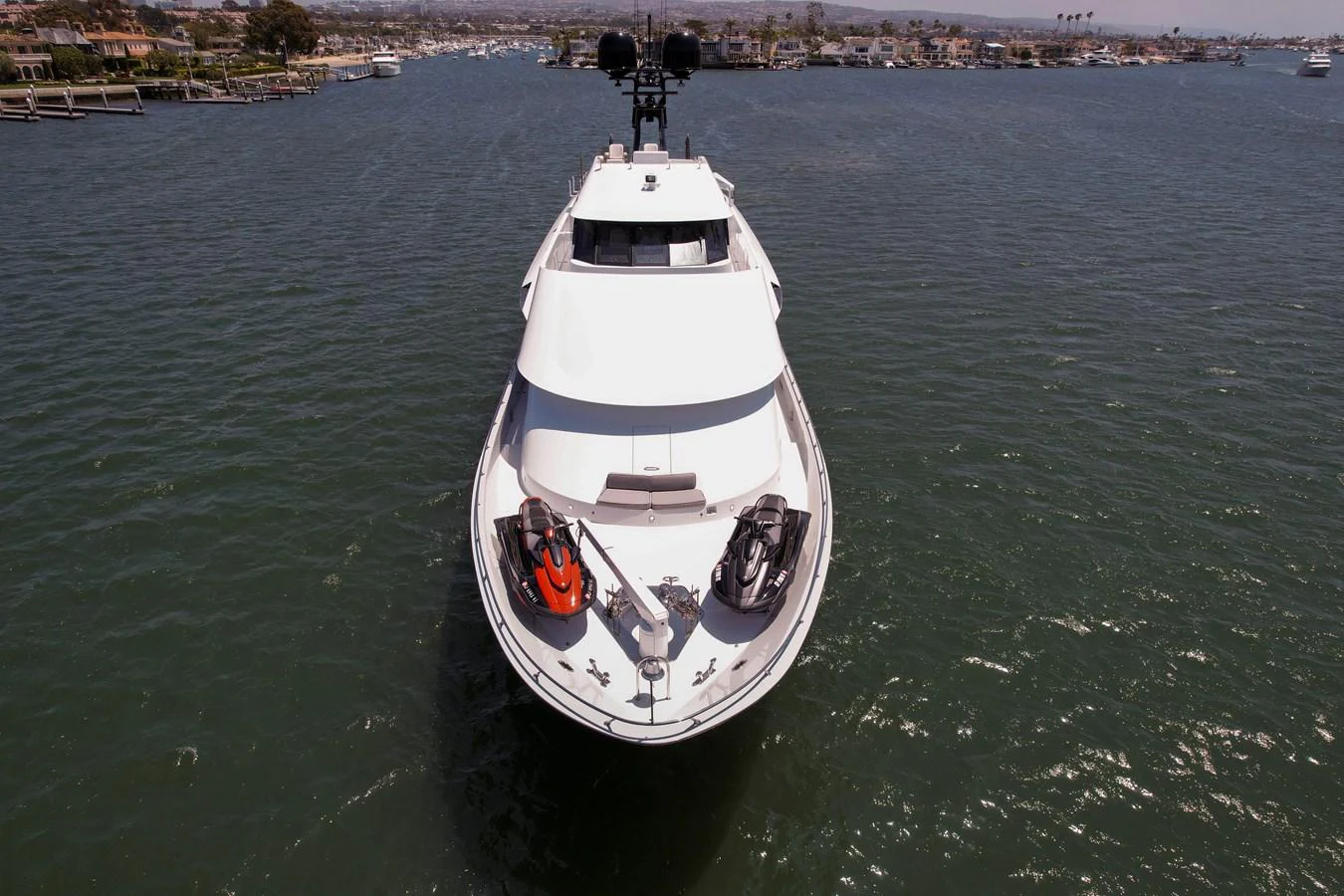A sleek yacht is anchored in a serene harbor, showcasing its modern design and water toys on the bow. aboard GOLDEN BOY II Yacht for Sale