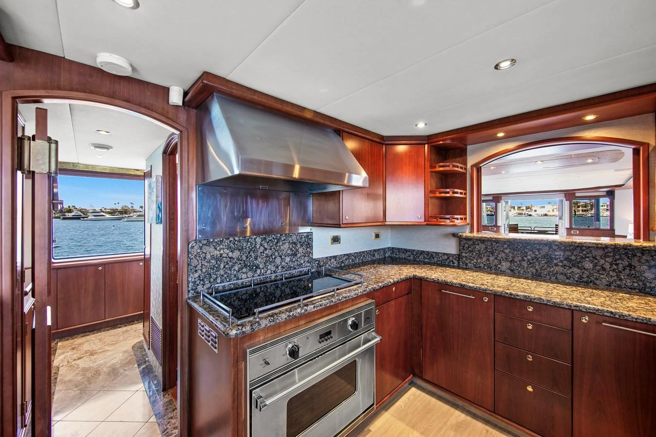 The galley features rich wood cabinetry, granite countertops, and modern appliances, with a view of the water through the windows. aboard GOLDEN BOY II Yacht for Sale