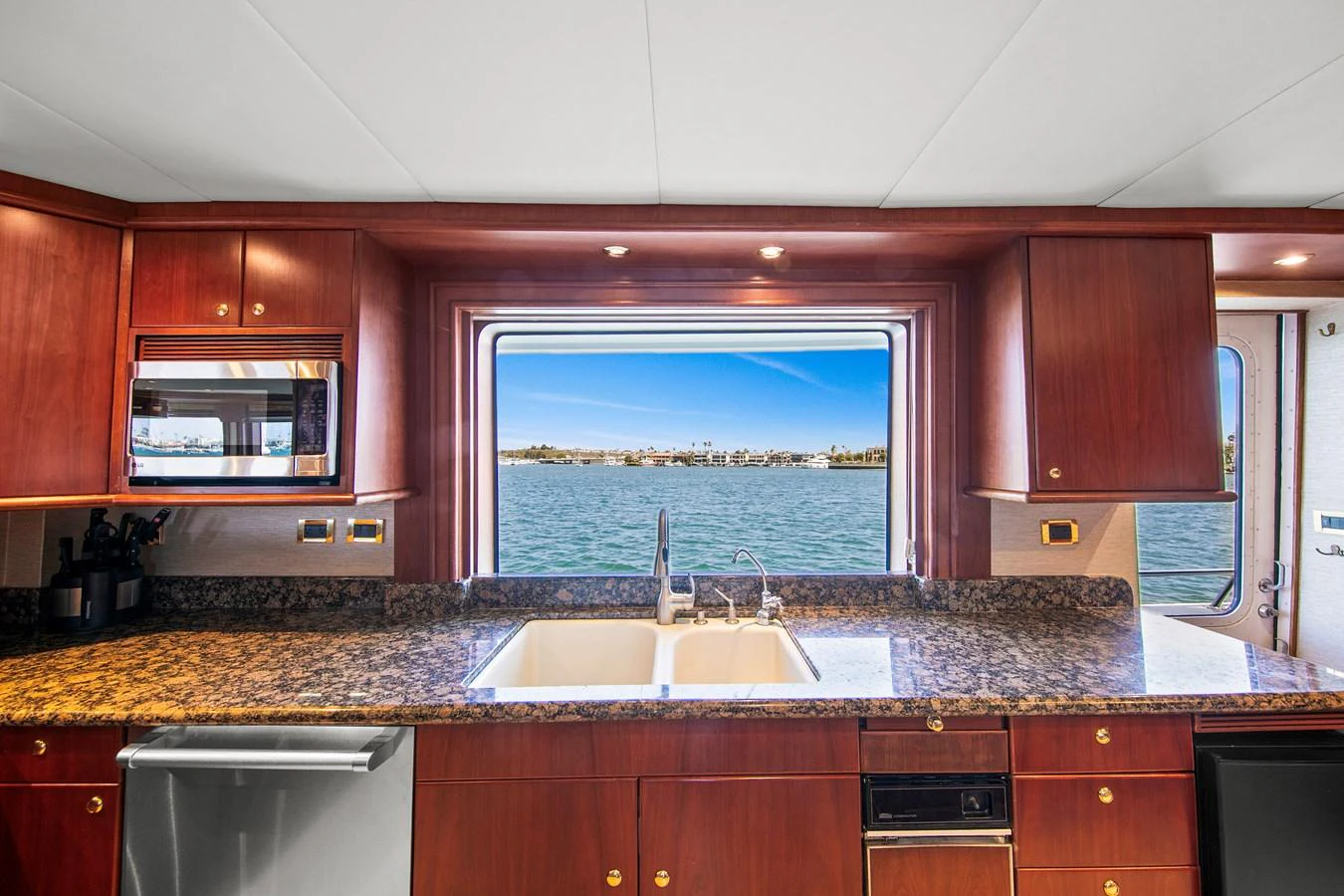 The galley features rich wood cabinetry, modern appliances, and a stunning view of the water. aboard GOLDEN BOY II Yacht for Sale