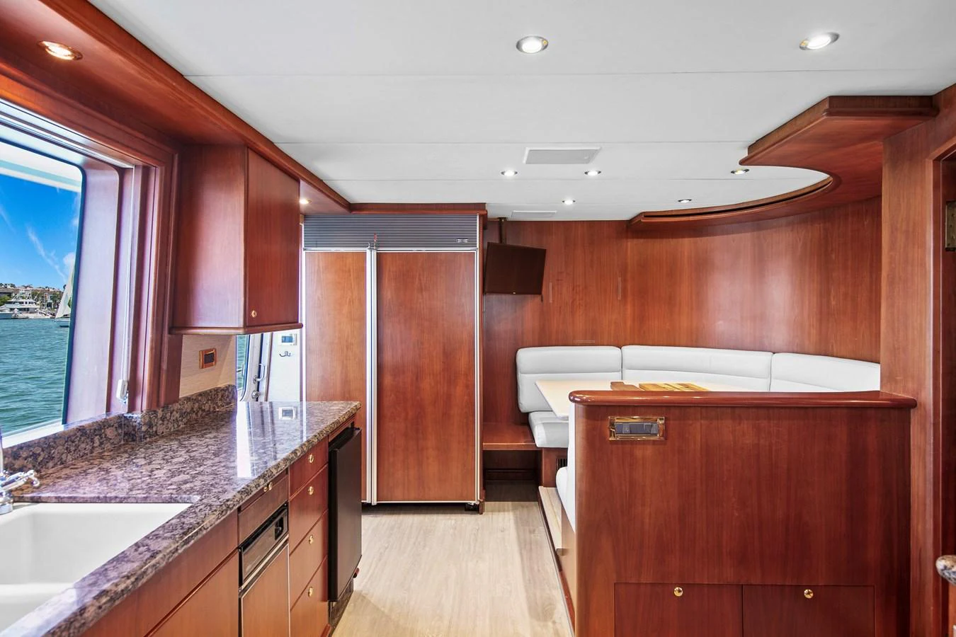 The yacht's galley features rich wood cabinetry, modern appliances, and a cozy dining nook with a view of the water. aboard GOLDEN BOY II Yacht for Sale