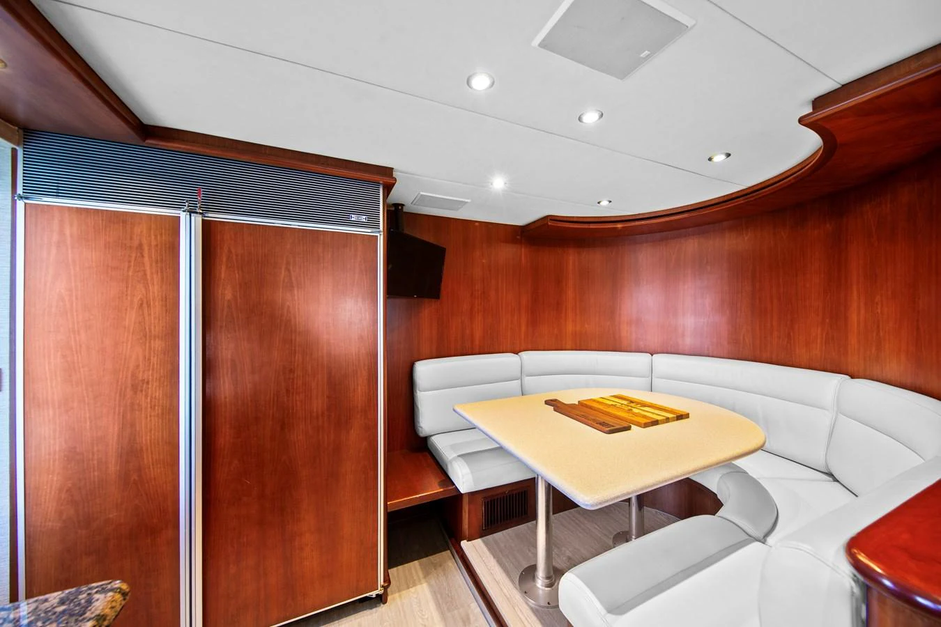 The yacht's dining area features a cozy, curved seating arrangement with a sleek wooden table. aboard GOLDEN BOY II Yacht for Sale