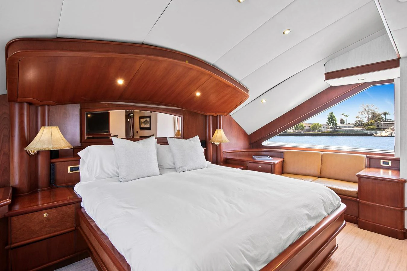 The master stateroom features a luxurious bed with elegant wooden finishes and a scenic view through large windows. aboard GOLDEN BOY II Yacht for Sale