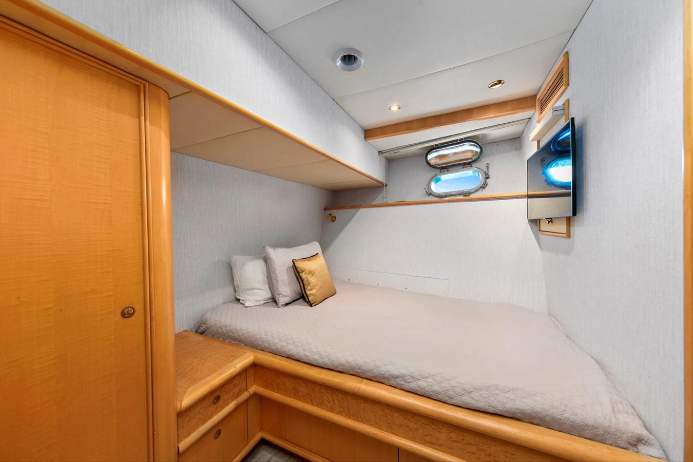 A cozy guest stateroom featuring a comfortable bed, wooden cabinetry, and a porthole window. aboard GOLDEN BOY II Yacht for Sale
