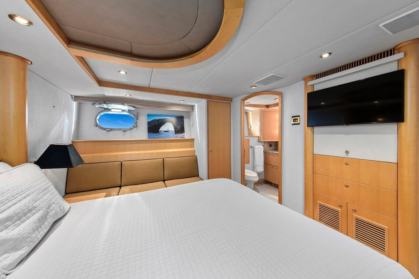 The stateroom features a comfortable bed, a wall-mounted TV, and a private bathroom. aboard GOLDEN BOY II Yacht for Sale