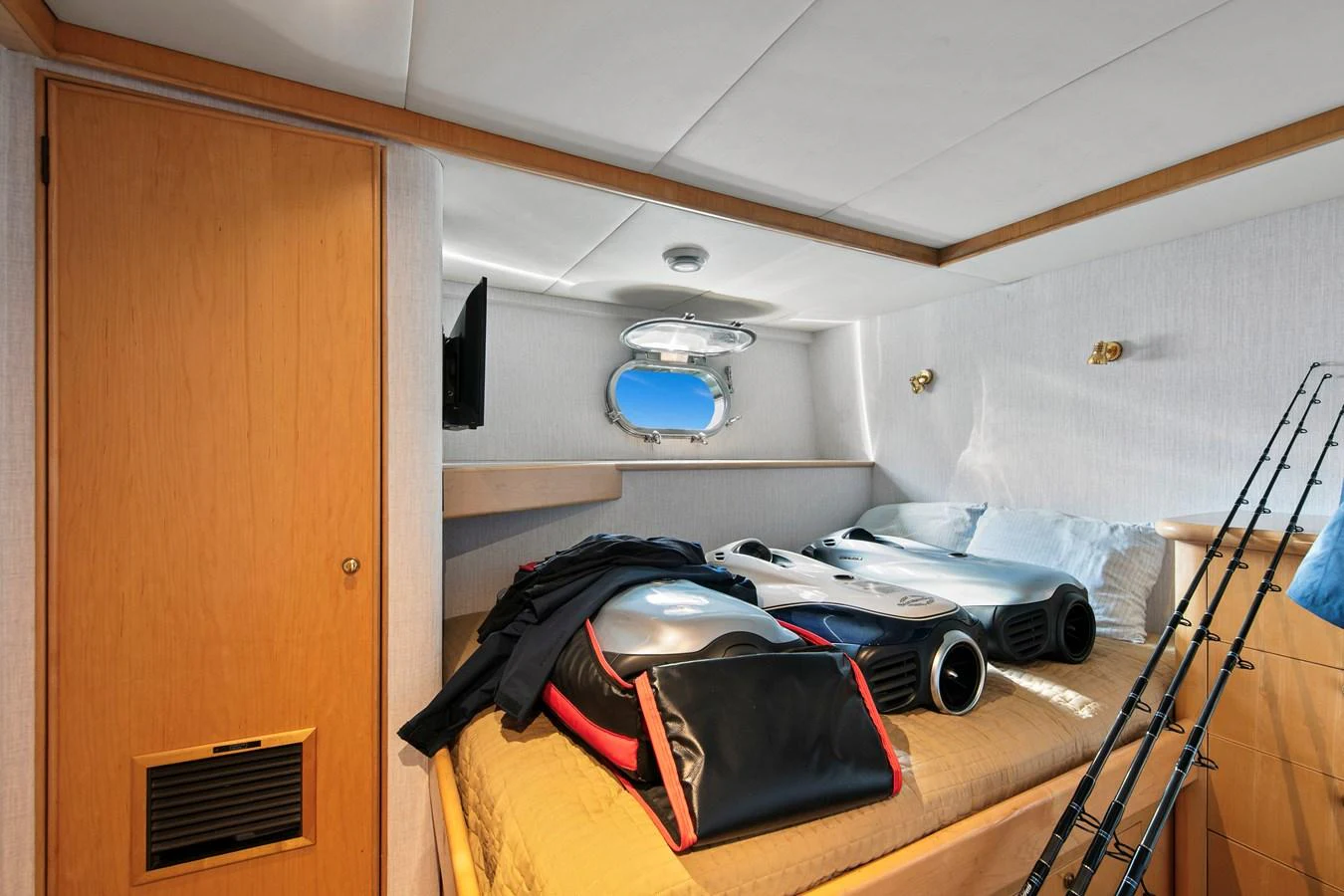 A cozy cabin with a small porthole, neatly arranged with personal items and fishing gear. aboard GOLDEN BOY II Yacht for Sale