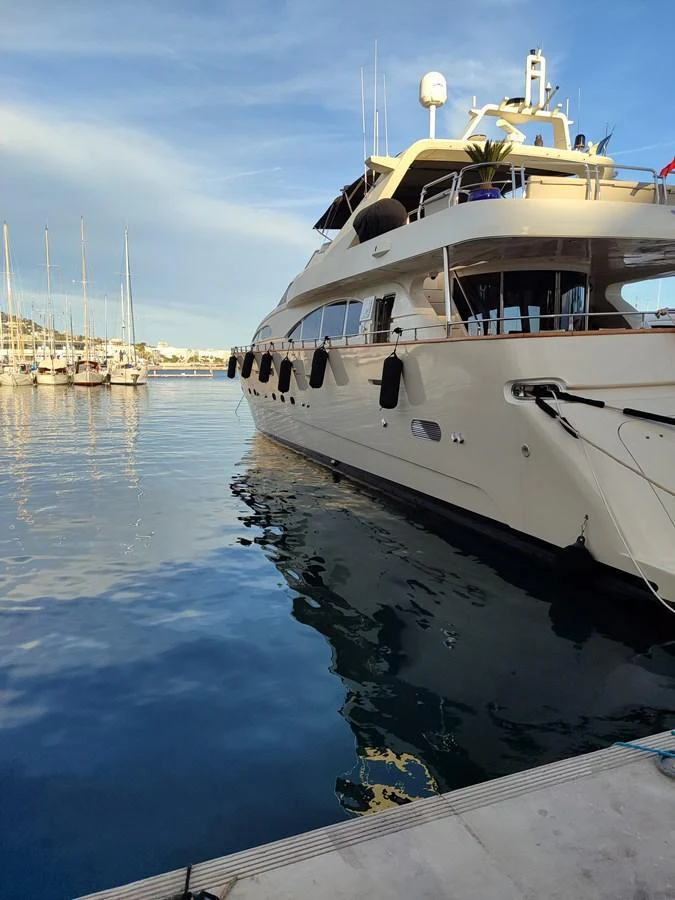 A luxurious yacht is docked at the marina, reflecting beautifully on the calm water. aboard ACCAMA DELTA Yacht for Sale