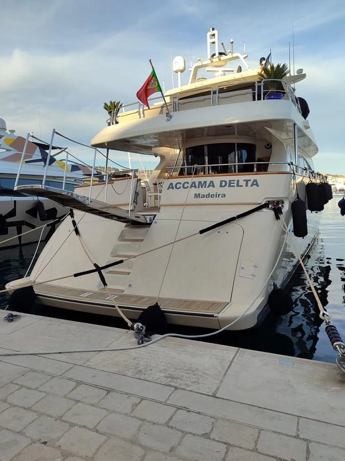 The yacht is docked, showcasing its elegant aft deck and inviting boarding steps. aboard ACCAMA DELTA Yacht for Sale