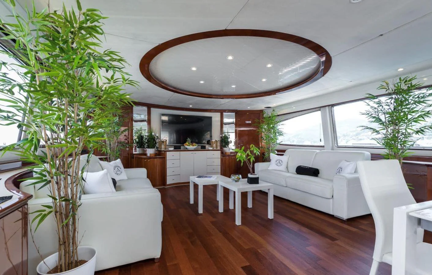 The salon features elegant white seating, lush greenery, and ample natural light, creating a serene and inviting atmosphere. aboard ACCAMA DELTA Yacht for Sale