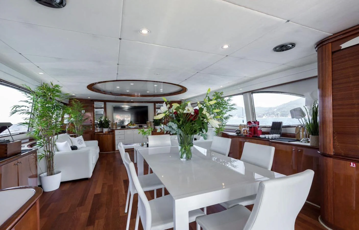 The yacht's dining area features a sleek white table surrounded by modern chairs, with large windows offering scenic views. aboard ACCAMA DELTA Yacht for Sale