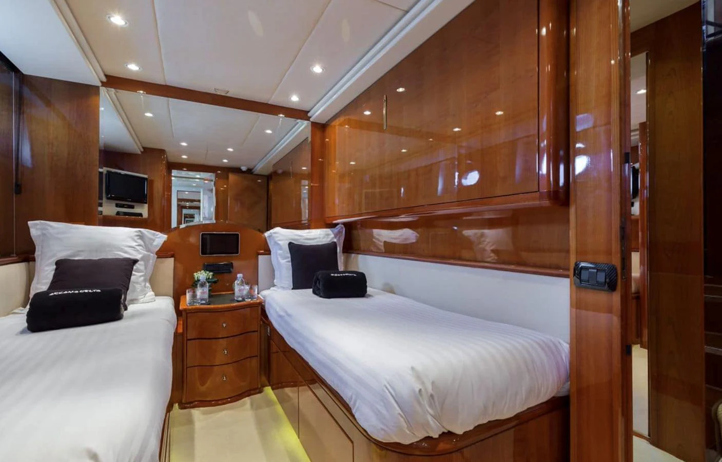 The twin stateroom features two single beds with luxurious bedding and elegant wood paneling. aboard ACCAMA DELTA Yacht for Sale