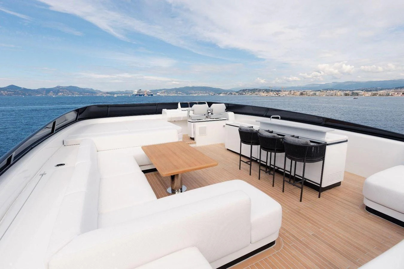 The flybridge offers a spacious seating area with a dining table and bar stools, perfect for enjoying panoramic views. aboard MINI Yacht for Sale