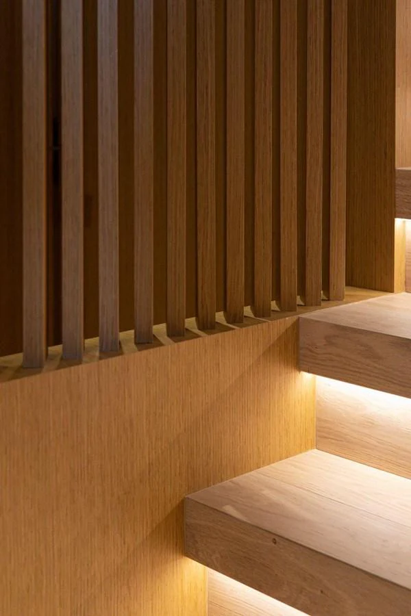 The image showcases a modern, wooden staircase with ambient lighting. aboard MINI Yacht for Sale