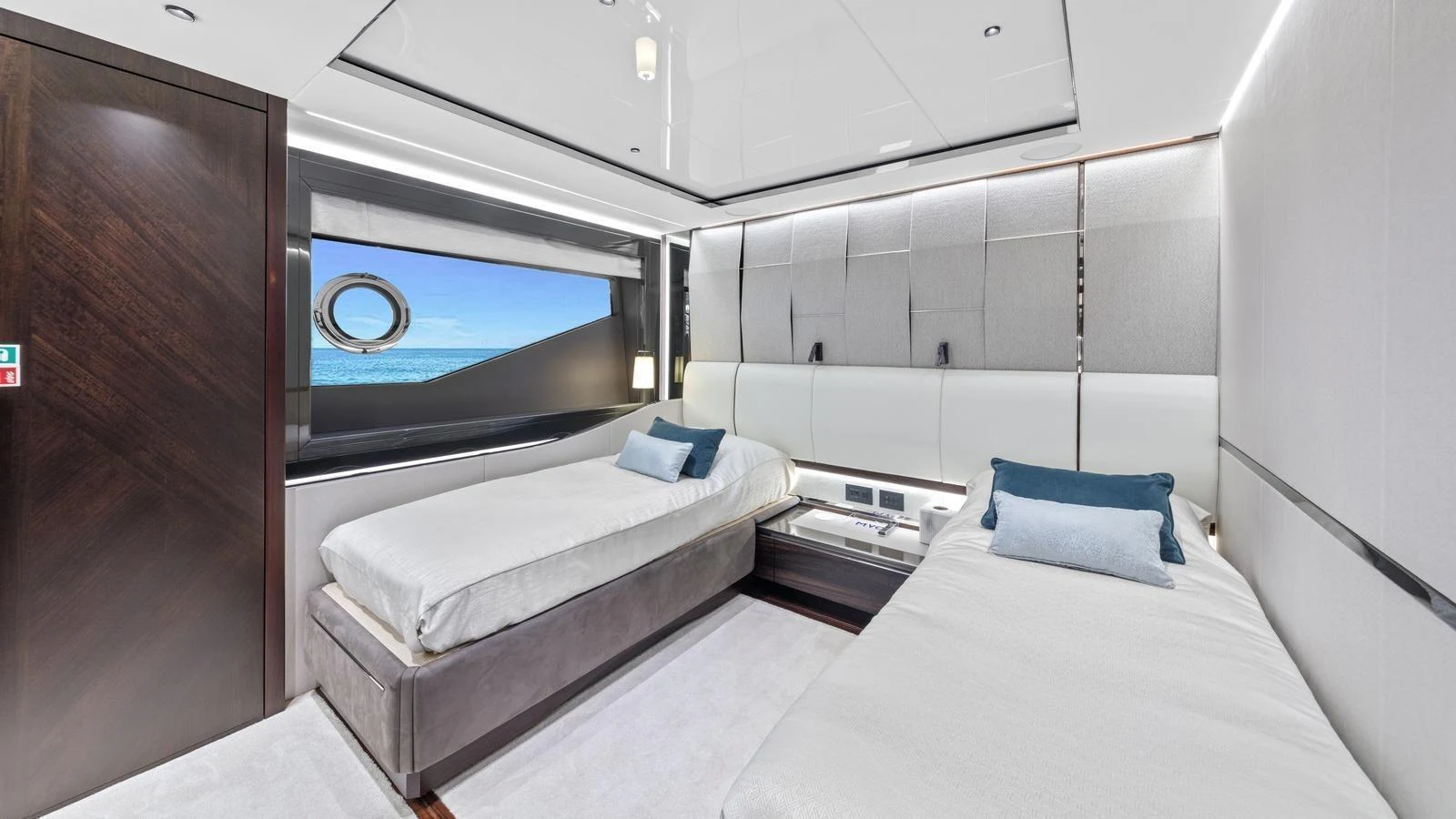 A modern guest stateroom featuring two single beds with elegant decor and a large window offering a view of the sea. aboard CONTESSA Yacht for Sale