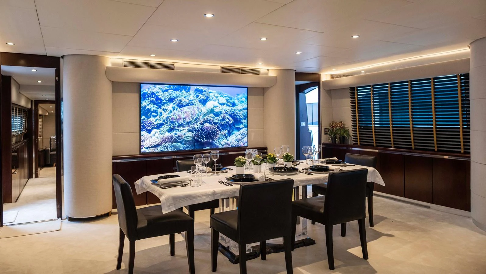 a table with chairs and a large screen in a room with a window aboard BELLINI Yacht for Sale