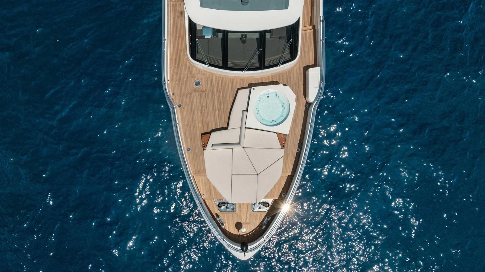 The yacht's foredeck features a luxurious sunbathing area and a jacuzzi, set against the backdrop of the sparkling blue sea. aboard ARIA Yacht for Sale