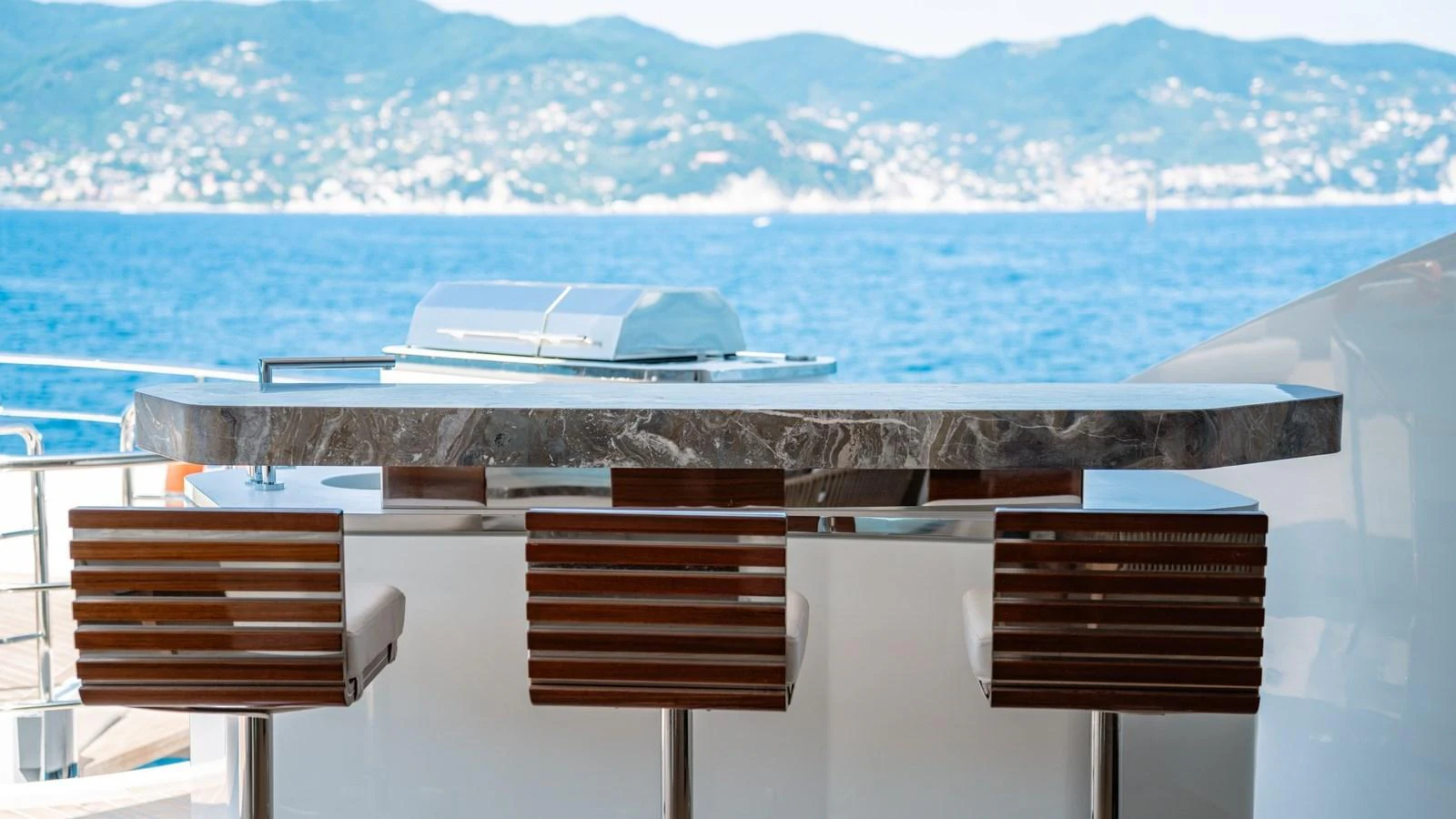 A sleek outdoor bar area with modern bar stools and a stunning ocean view. aboard ARIA Yacht for Sale
