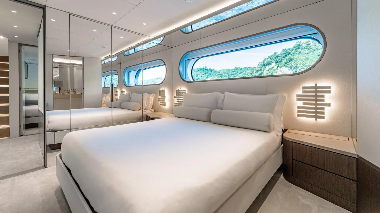 A luxurious stateroom with a large bed, mirrored walls, and scenic windows. aboard ARIA Yacht for Sale