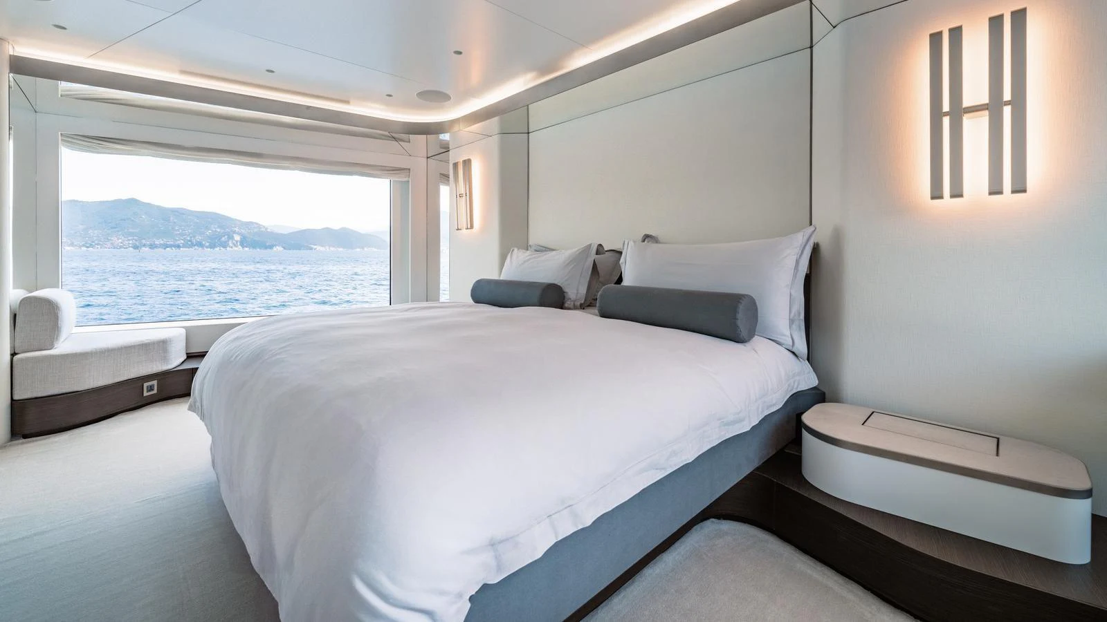 The master stateroom features a large bed with a stunning ocean view through a wide window. aboard ARIA Yacht for Sale