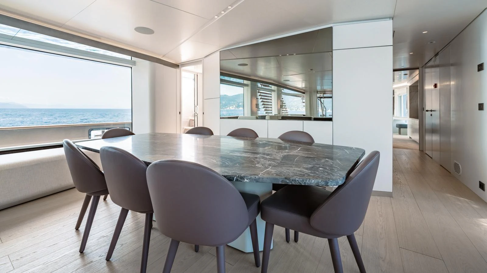 The yacht's dining area features a sleek, modern design with a large marble table and comfortable seating, offering stunning ocean views. aboard ARIA Yacht for Sale