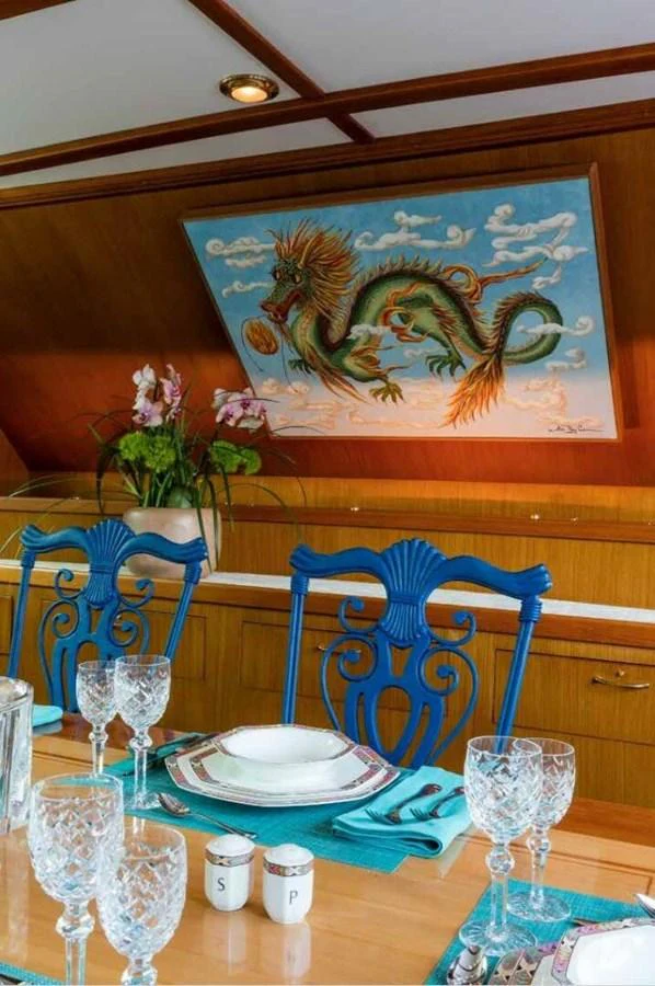 The yacht's dining area features elegant table settings and a striking dragon painting on the wall. aboard SEAFARI Yacht for Sale