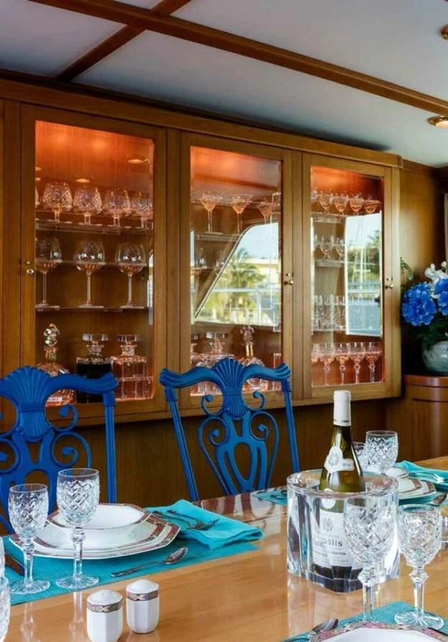 The yacht's dining area features elegant table settings and a well-stocked glass cabinet. aboard SEAFARI Yacht for Sale