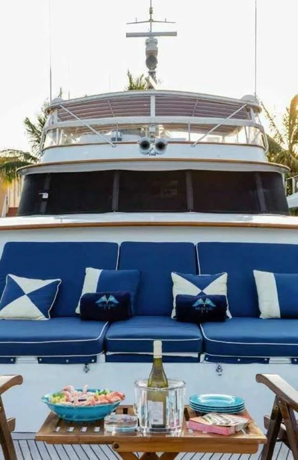 The yacht's bow area features a cozy seating arrangement with plush blue cushions and a small table set for refreshments. aboard SEAFARI Yacht for Sale