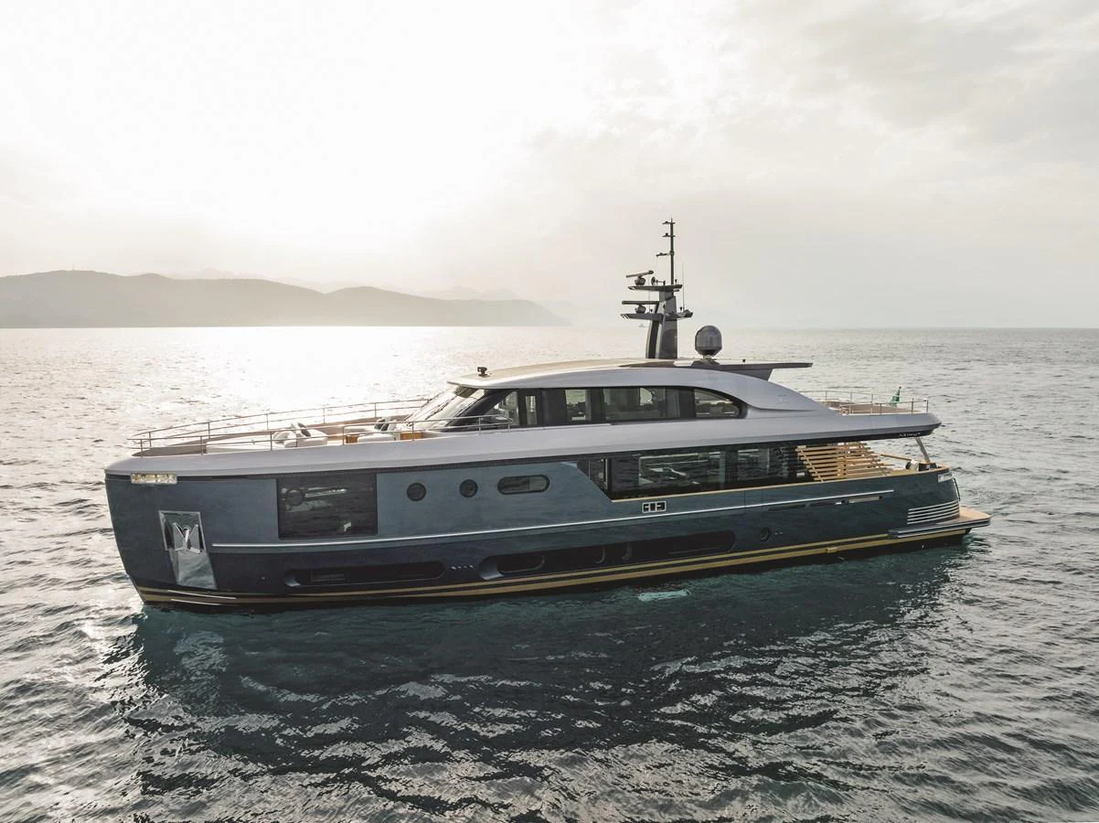 A sleek and modern yacht glides gracefully on the open water with a stunning backdrop of distant mountains. aboard PALMAX Yacht for Sale