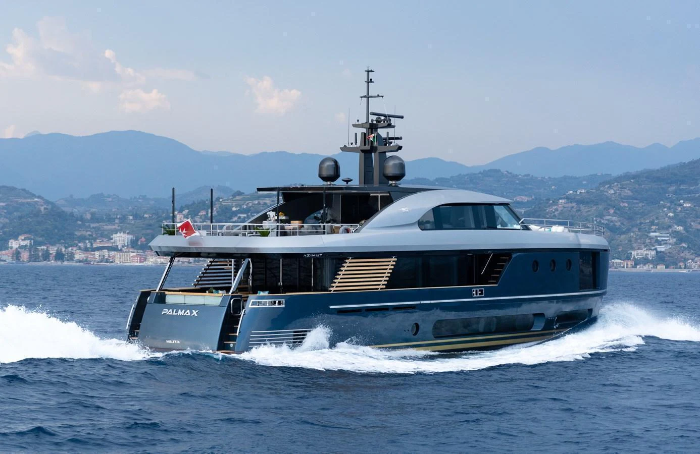 A sleek and modern yacht cruising on the open water with a scenic coastal backdrop. aboard PALMAX Yacht for Sale