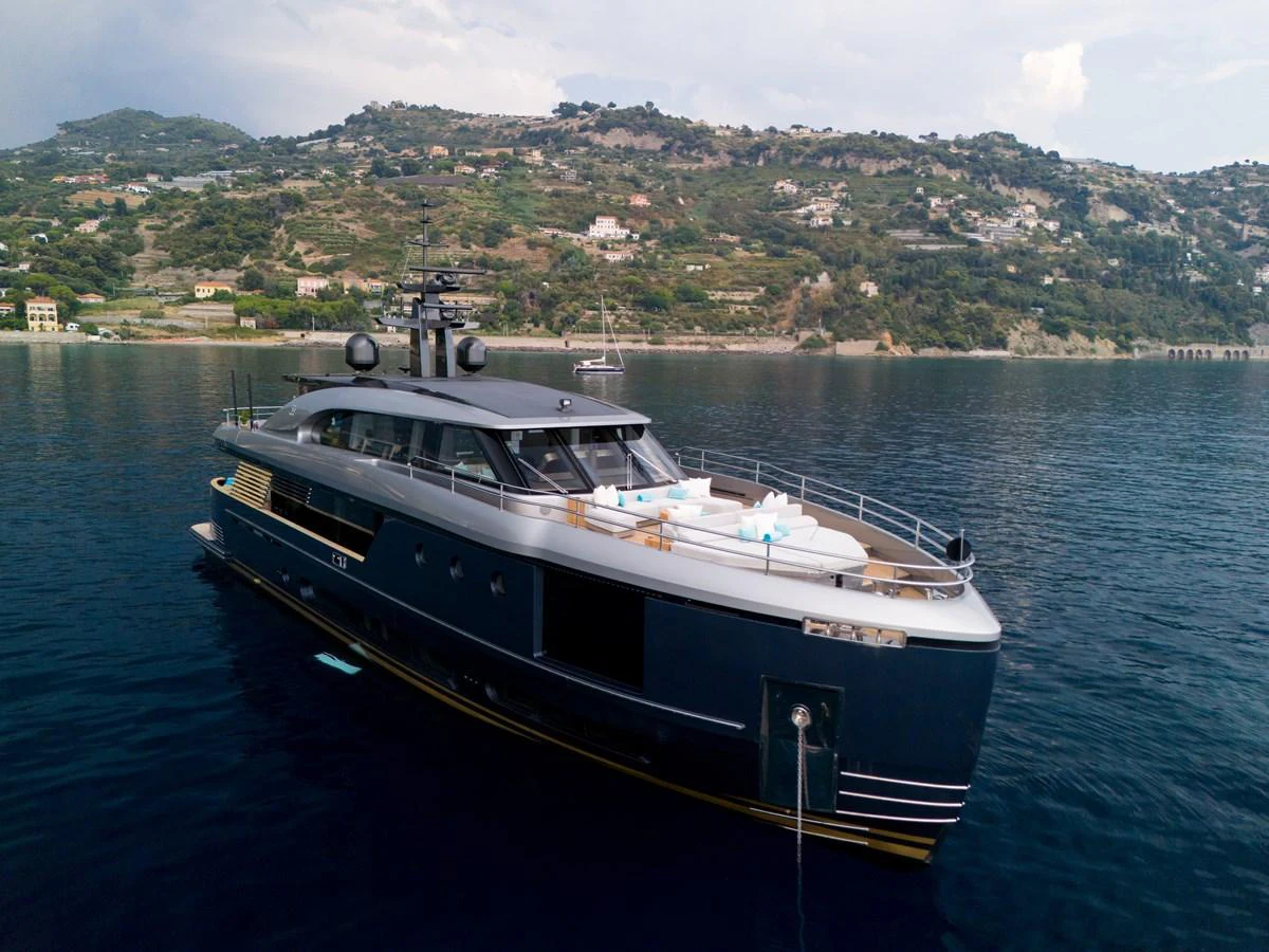 A sleek and modern yacht is anchored in calm waters with a scenic coastal backdrop. aboard PALMAX Yacht for Sale