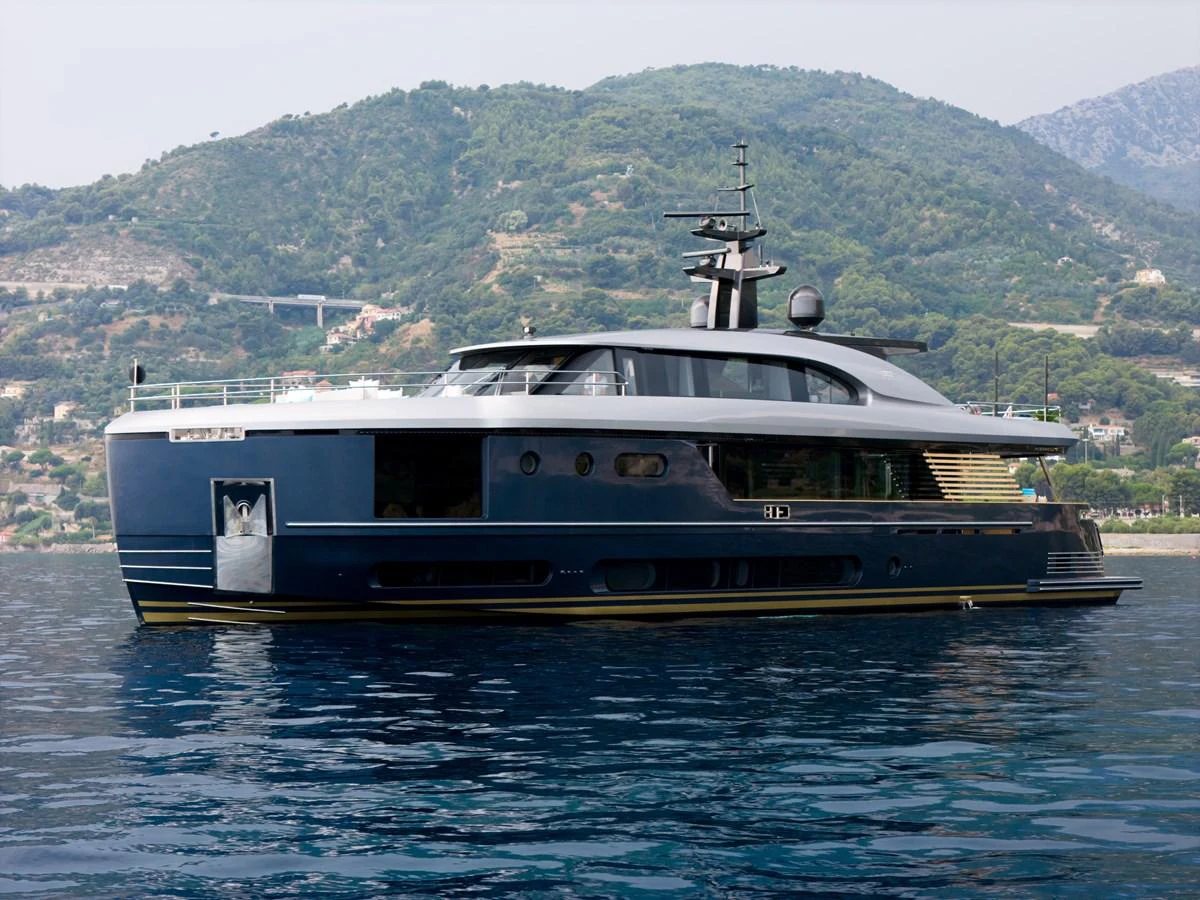 A sleek and modern yacht cruising on calm waters with a scenic mountainous backdrop. aboard PALMAX Yacht for Sale