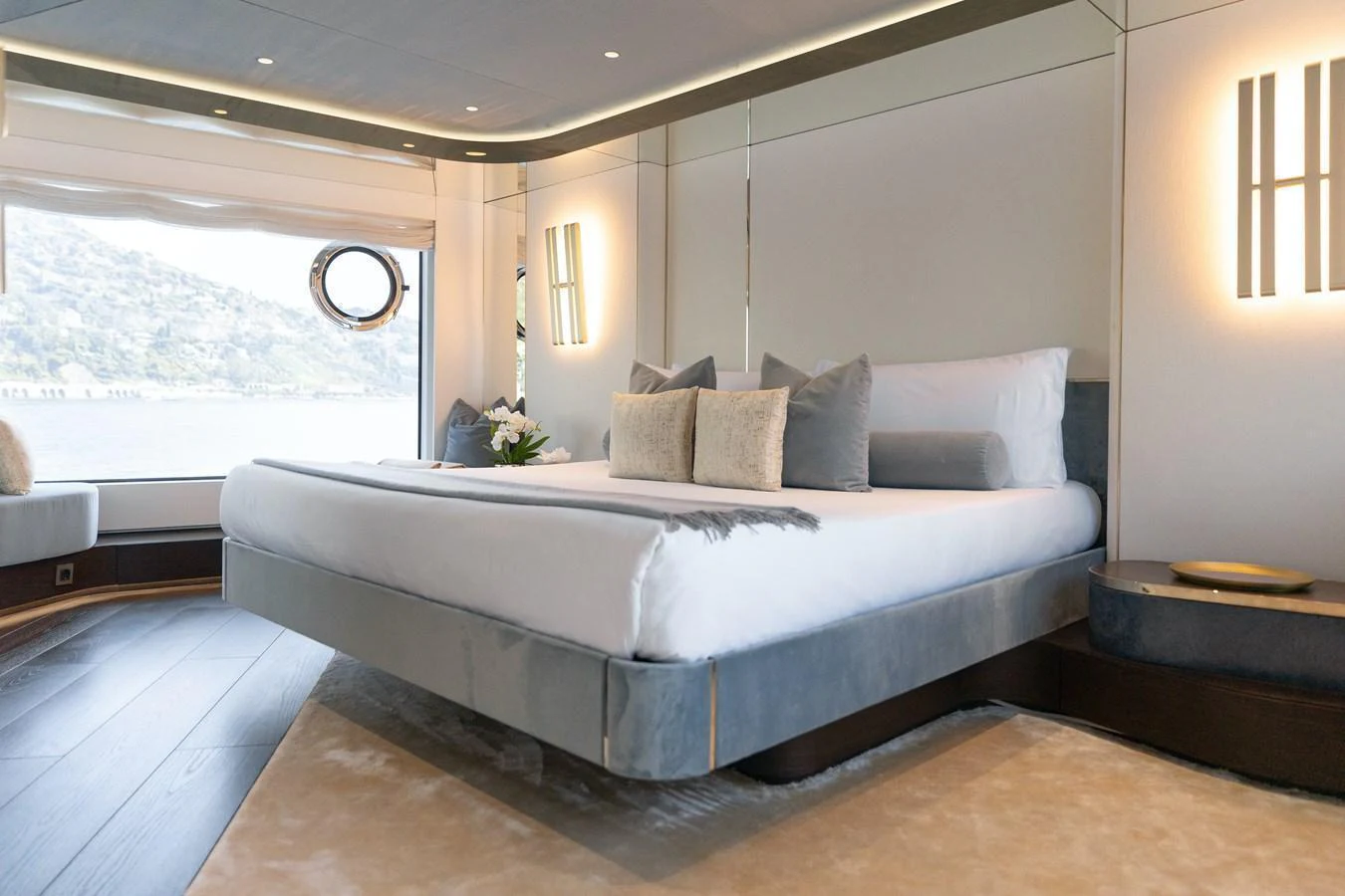 The master stateroom features a luxurious bed with elegant decor and a scenic view through the large window. aboard PALMAX Yacht for Sale