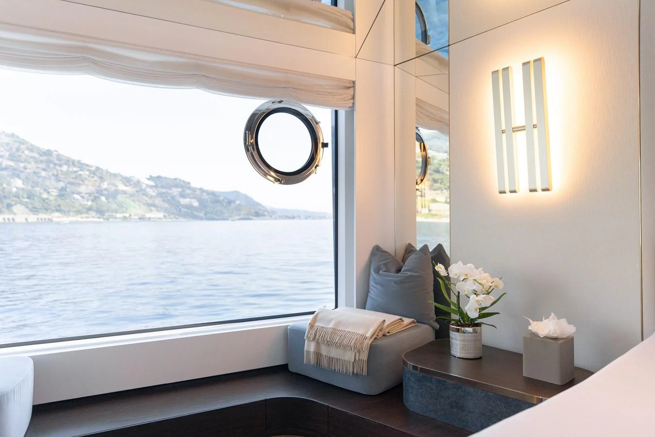 A serene interior space with a cozy seating area and a large window offering a scenic view of the water. aboard PALMAX Yacht for Sale