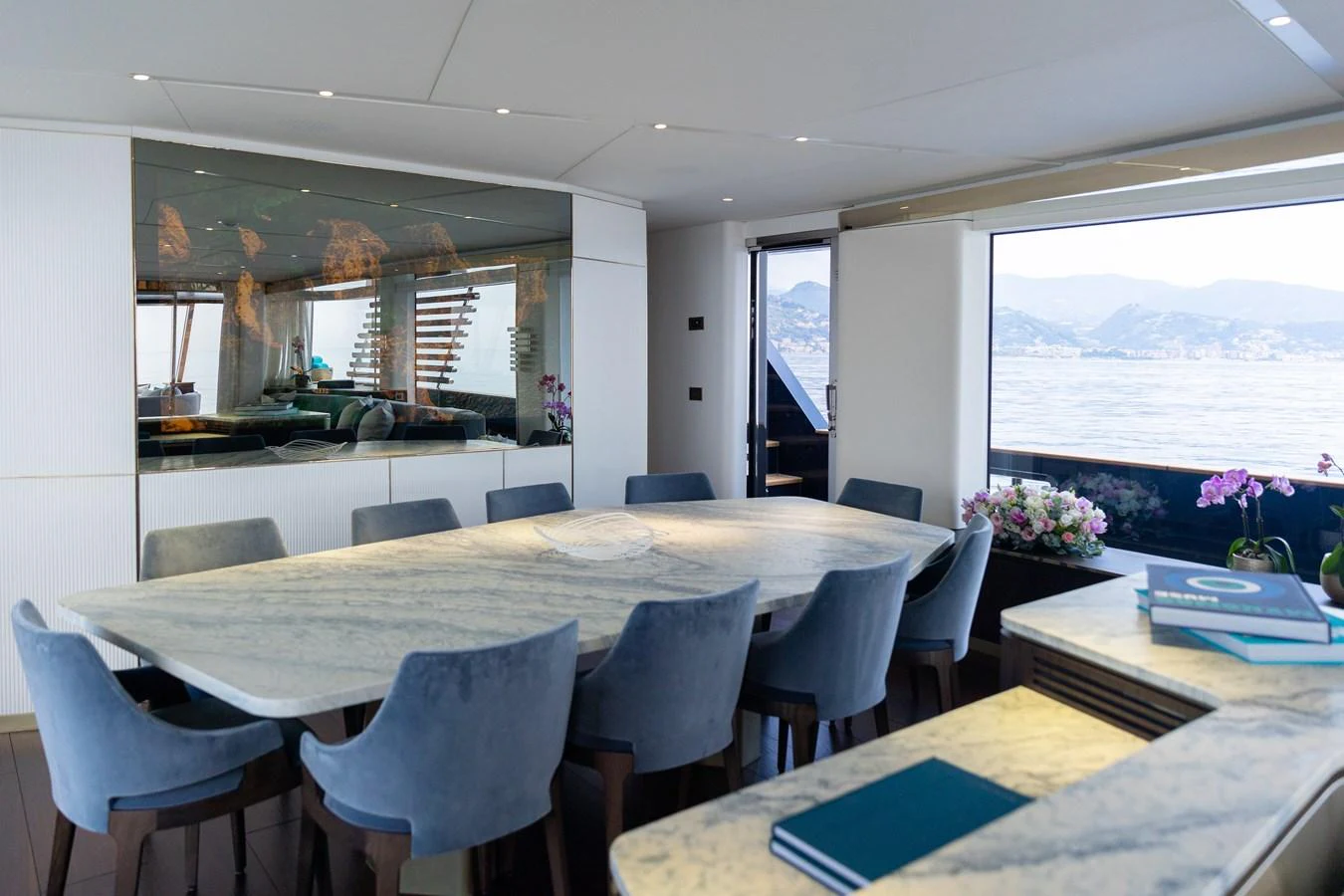 The yacht's dining area features a large marble table surrounded by plush chairs, with expansive windows offering stunning sea views. aboard PALMAX Yacht for Sale