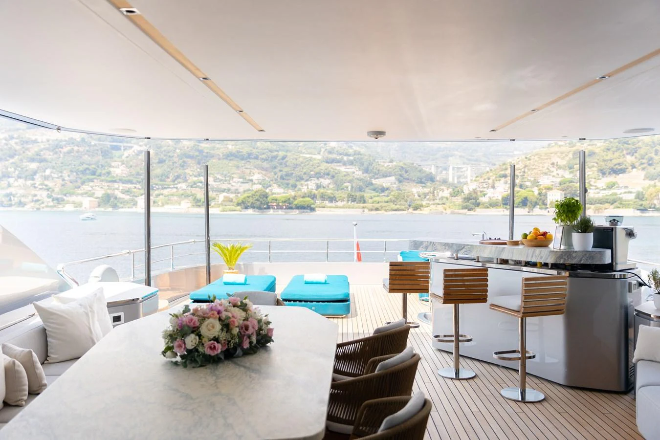The aft deck features a luxurious dining area with a stunning view of the water and surrounding landscape. aboard PALMAX Yacht for Sale