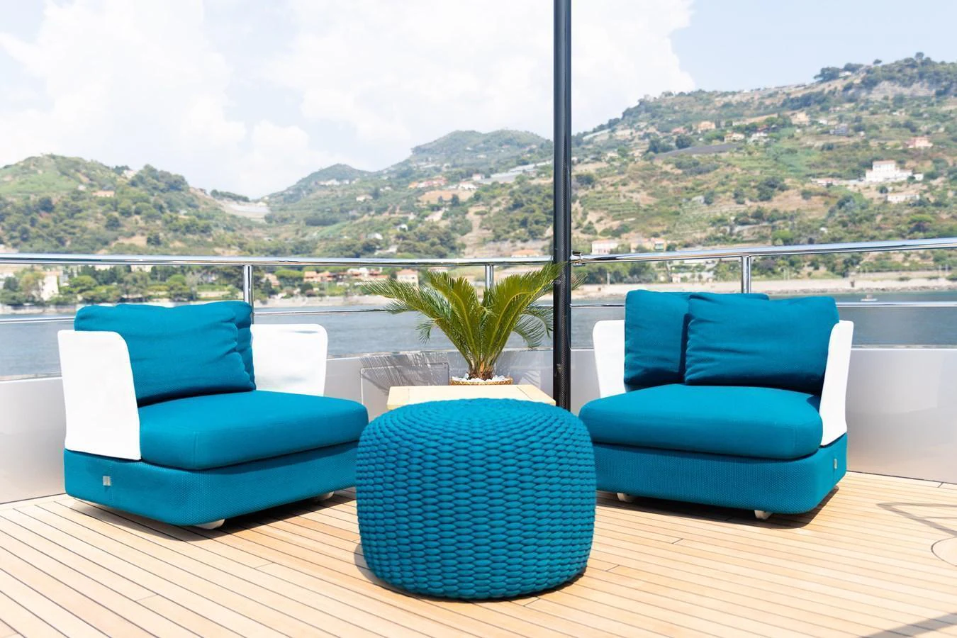 A stylish deck seating area with vibrant blue cushions and a scenic backdrop. aboard PALMAX Yacht for Sale
