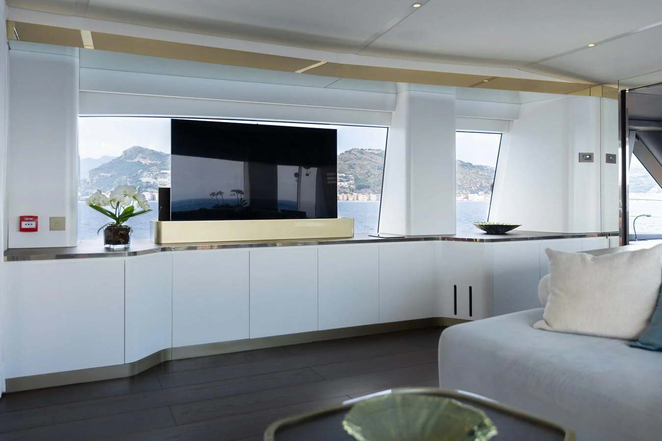 The yacht's interior features a modern entertainment area with a large TV and panoramic windows offering scenic views. aboard PALMAX Yacht for Sale