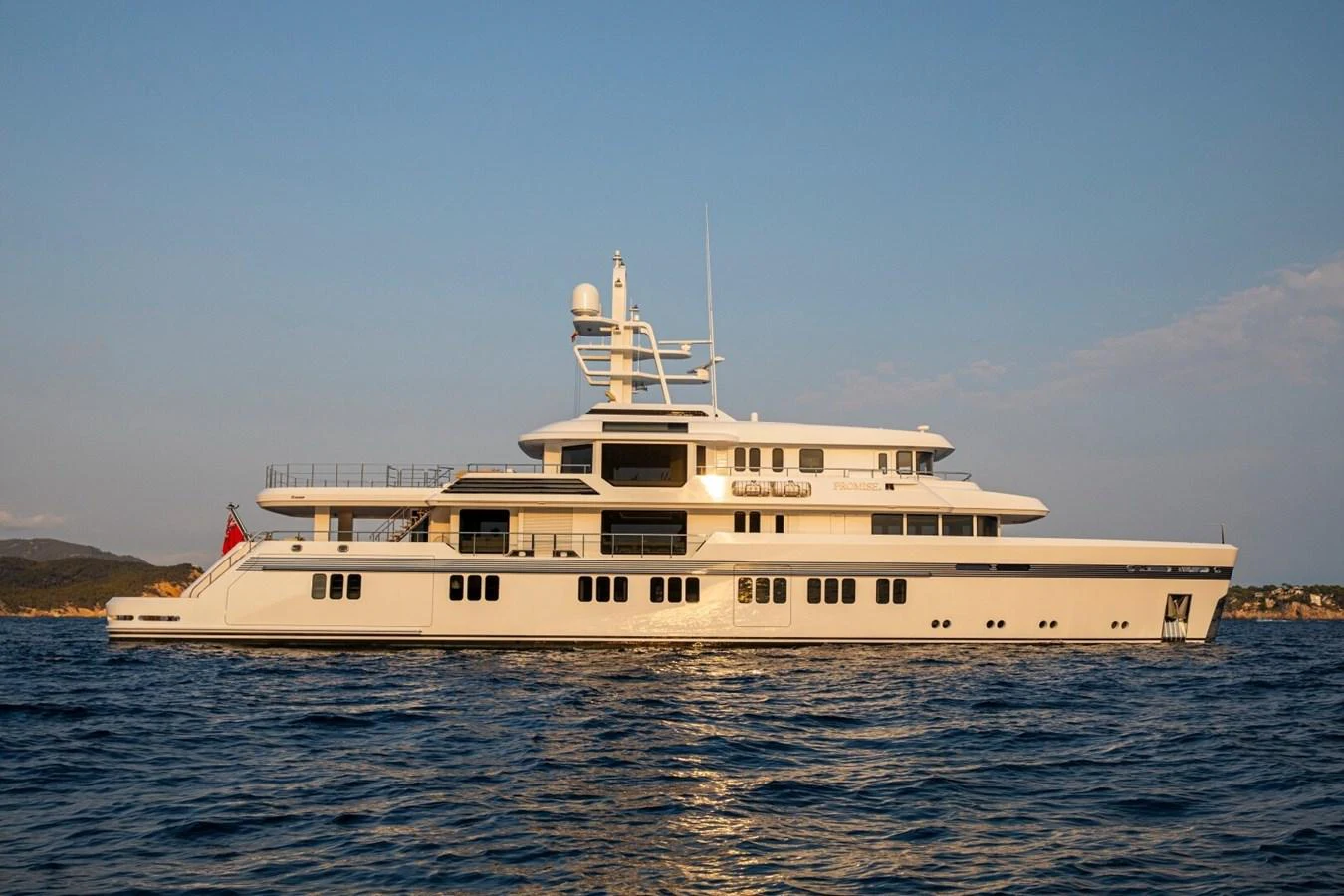 A luxurious yacht is gracefully anchored on calm waters during a beautiful sunset. aboard PROMISE Yacht for Sale