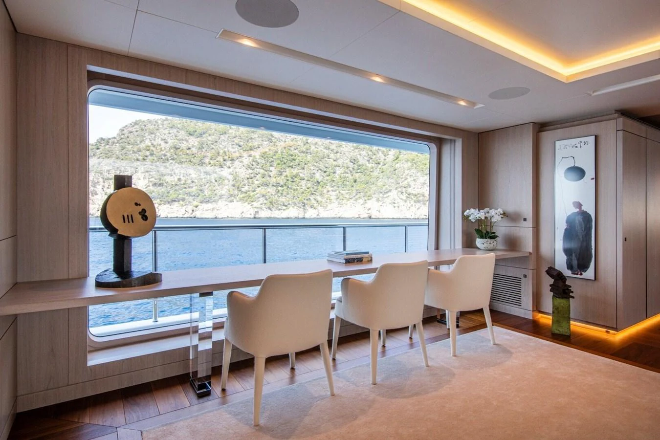 A serene office space with a large window offering a stunning view of the sea and surrounding landscape. aboard PROMISE Yacht for Sale