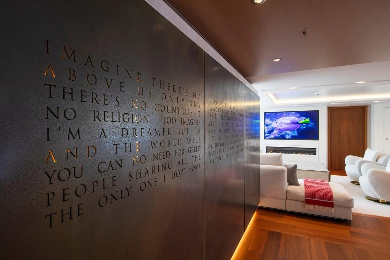 A luxurious yacht interior featuring a cozy lounge area with modern decor and a large wall art installation. aboard PROMISE Yacht for Sale
