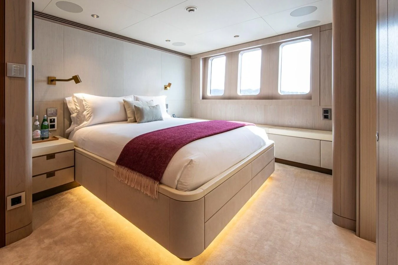 The stateroom features a luxurious bed with ambient lighting and large windows for natural light. aboard PROMISE Yacht for Sale