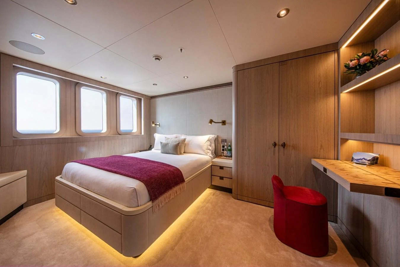 A luxurious stateroom featuring a comfortable bed with ambient lighting and elegant wooden furnishings. aboard PROMISE Yacht for Sale
