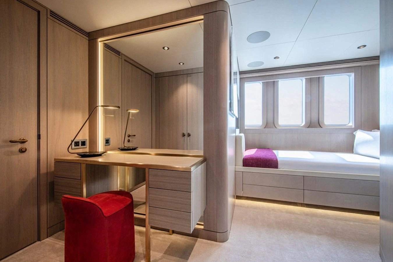 The stateroom features a sleek vanity area with a red chair and a comfortable bed by the window. aboard PROMISE Yacht for Sale