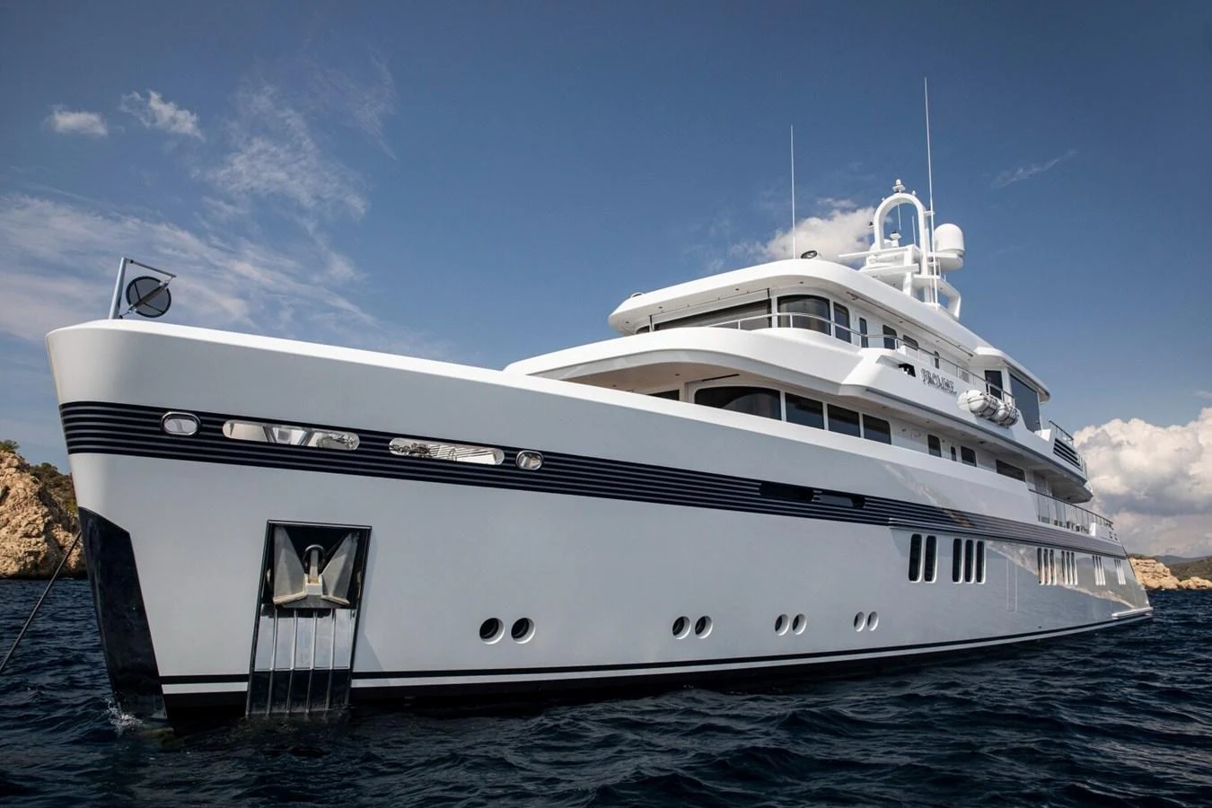A luxurious yacht glides gracefully on the water under a clear blue sky. aboard PROMISE Yacht for Sale