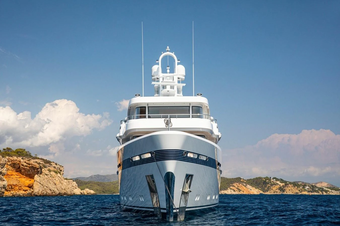 A stunning yacht is anchored in calm waters with a picturesque coastal backdrop. aboard PROMISE Yacht for Sale