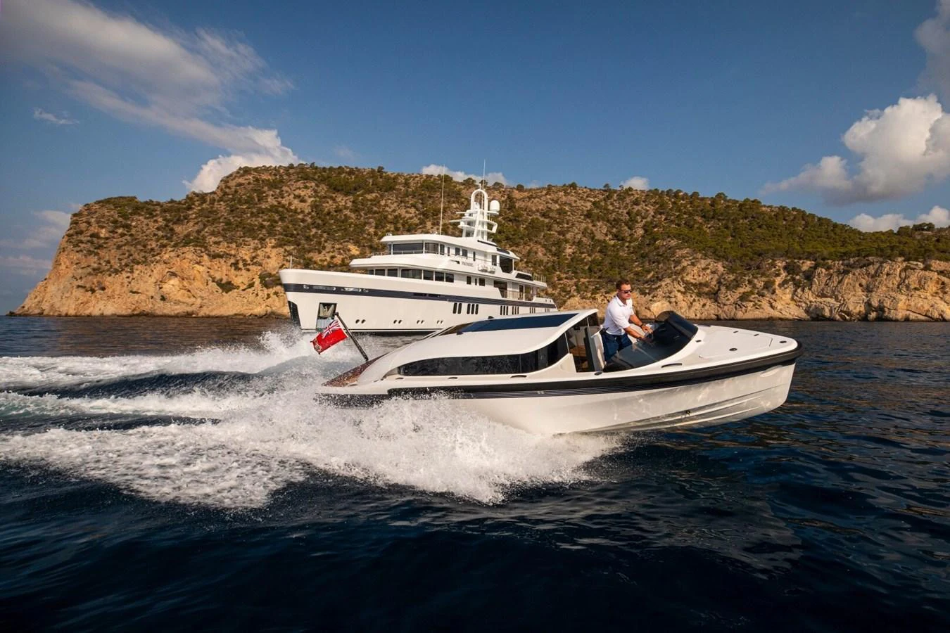 A sleek tender speeds across the water with a luxurious yacht in the background. aboard PROMISE Yacht for Sale
