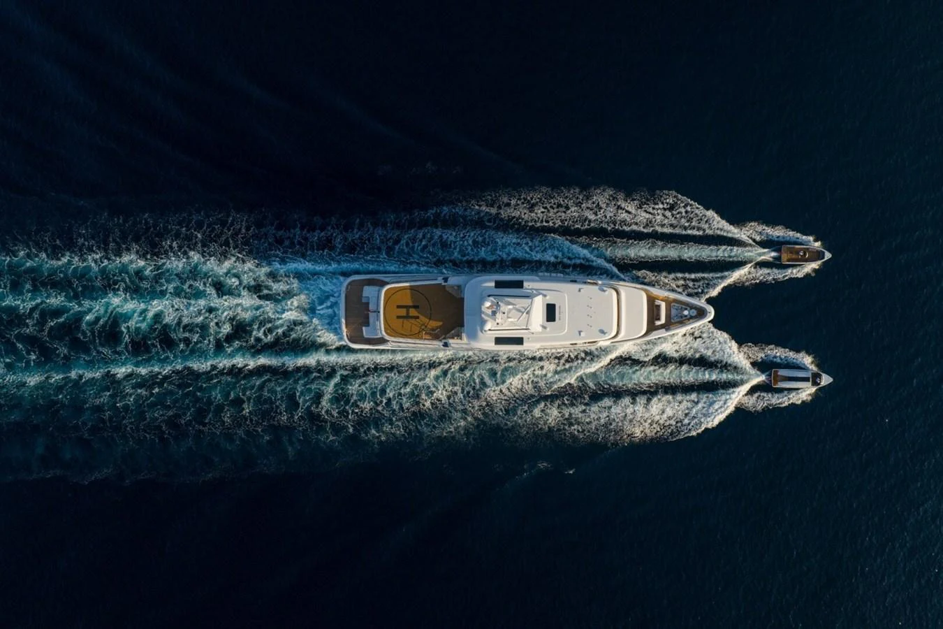 A stunning aerial view of a yacht cruising through the water with two tenders in tow. aboard PROMISE Yacht for Sale