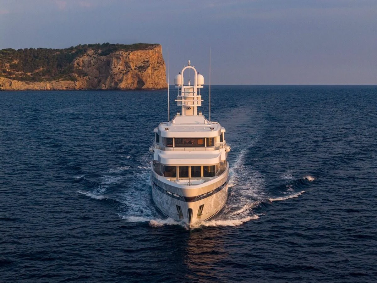 A luxurious yacht cruises through the open sea with a scenic coastline in the background. aboard PROMISE Yacht for Sale