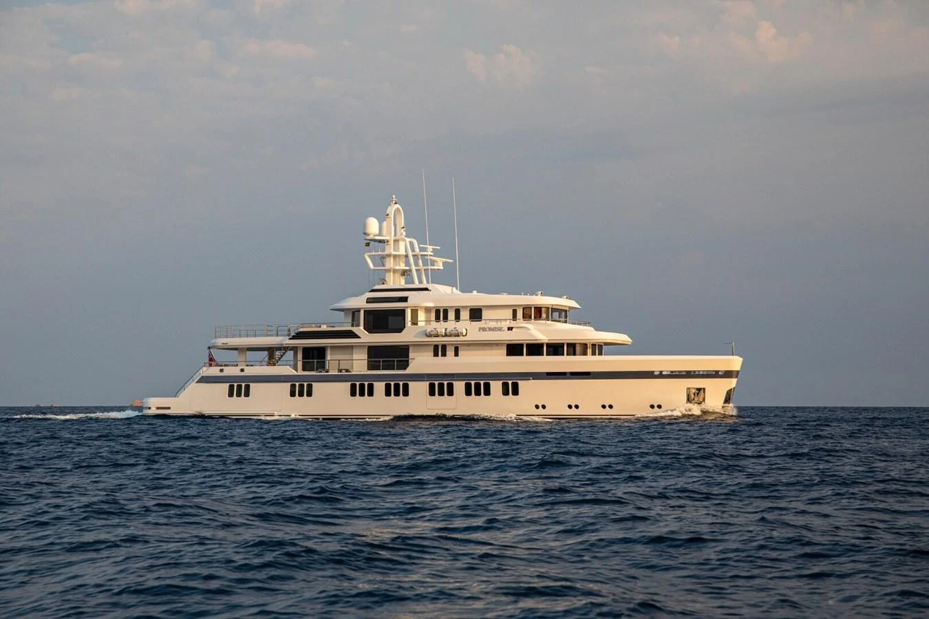 A luxurious yacht cruises gracefully on the open sea under a serene sky. aboard PROMISE Yacht for Sale