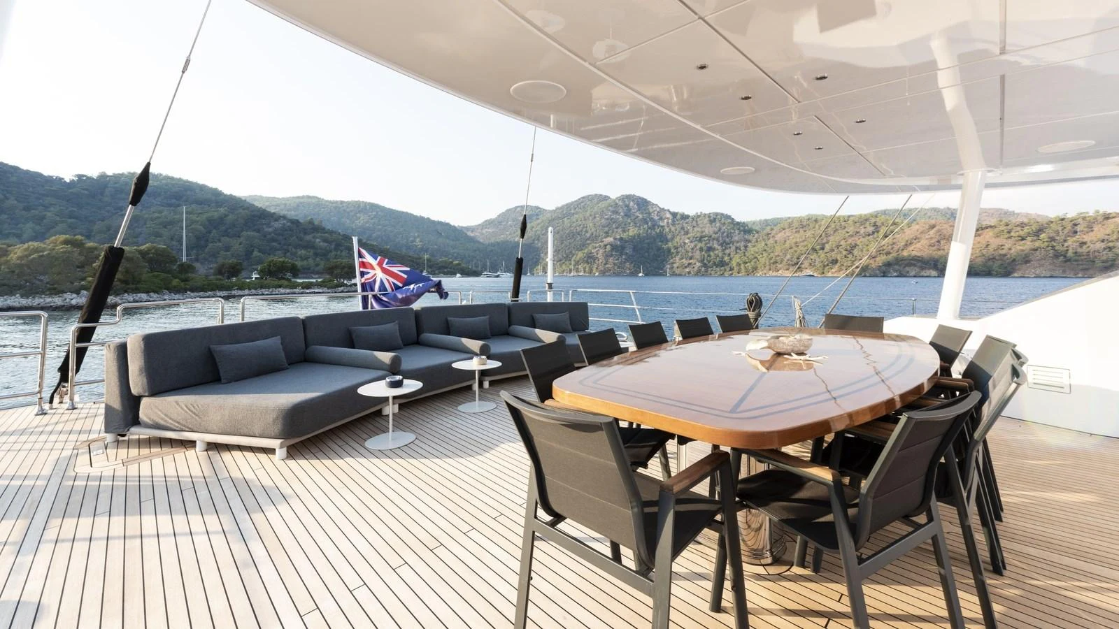 The aft deck features a spacious seating area with a large dining table, perfect for alfresco dining and relaxation. aboard ALL ABOUT U Yacht for Sale