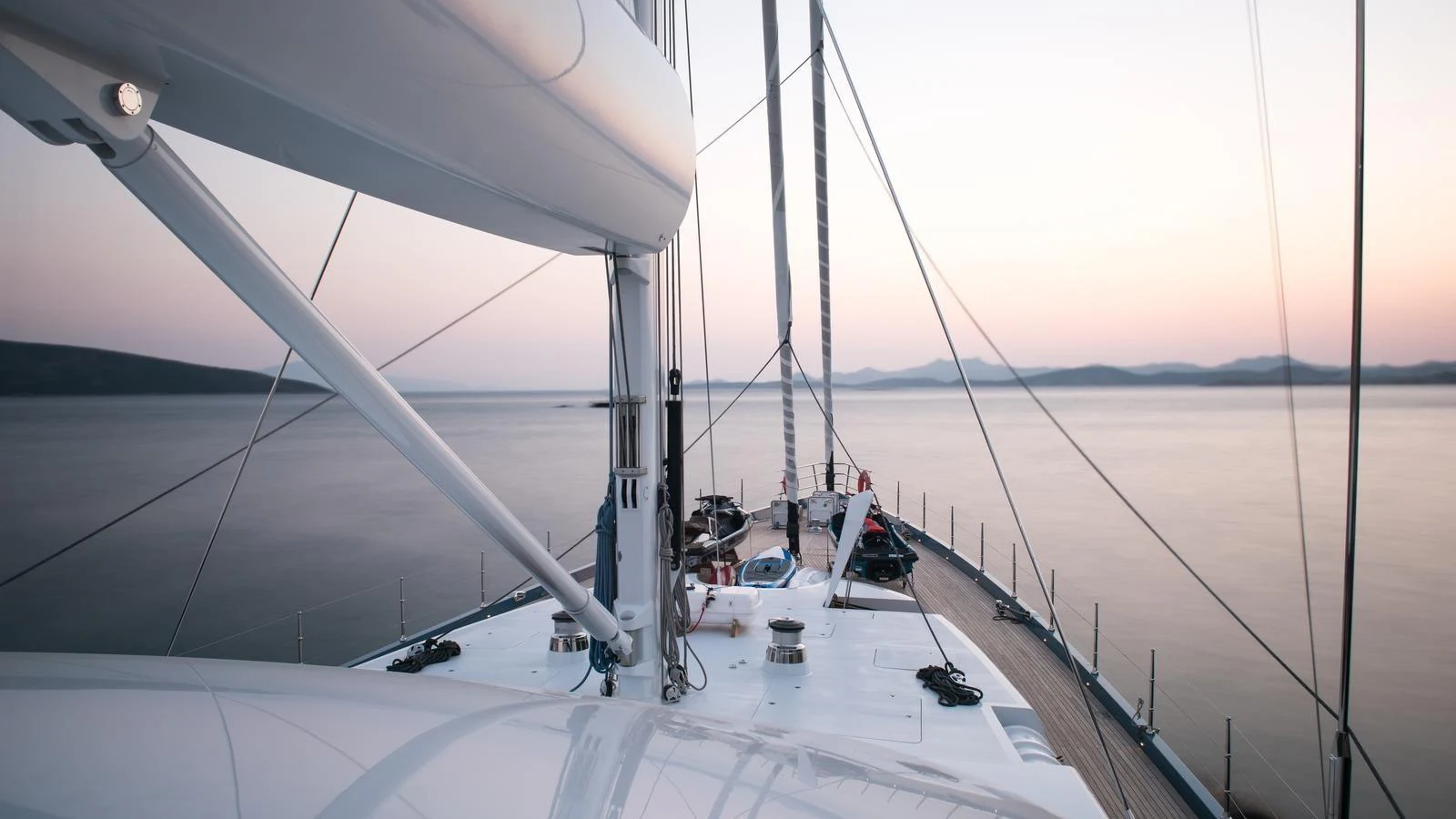 The foredeck of the yacht offers a serene view of the calm waters at dusk. aboard ALL ABOUT U Yacht for Sale